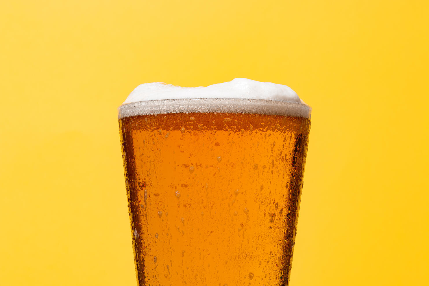 Playful image od beer glass full of beer on a bright yellow backgroun