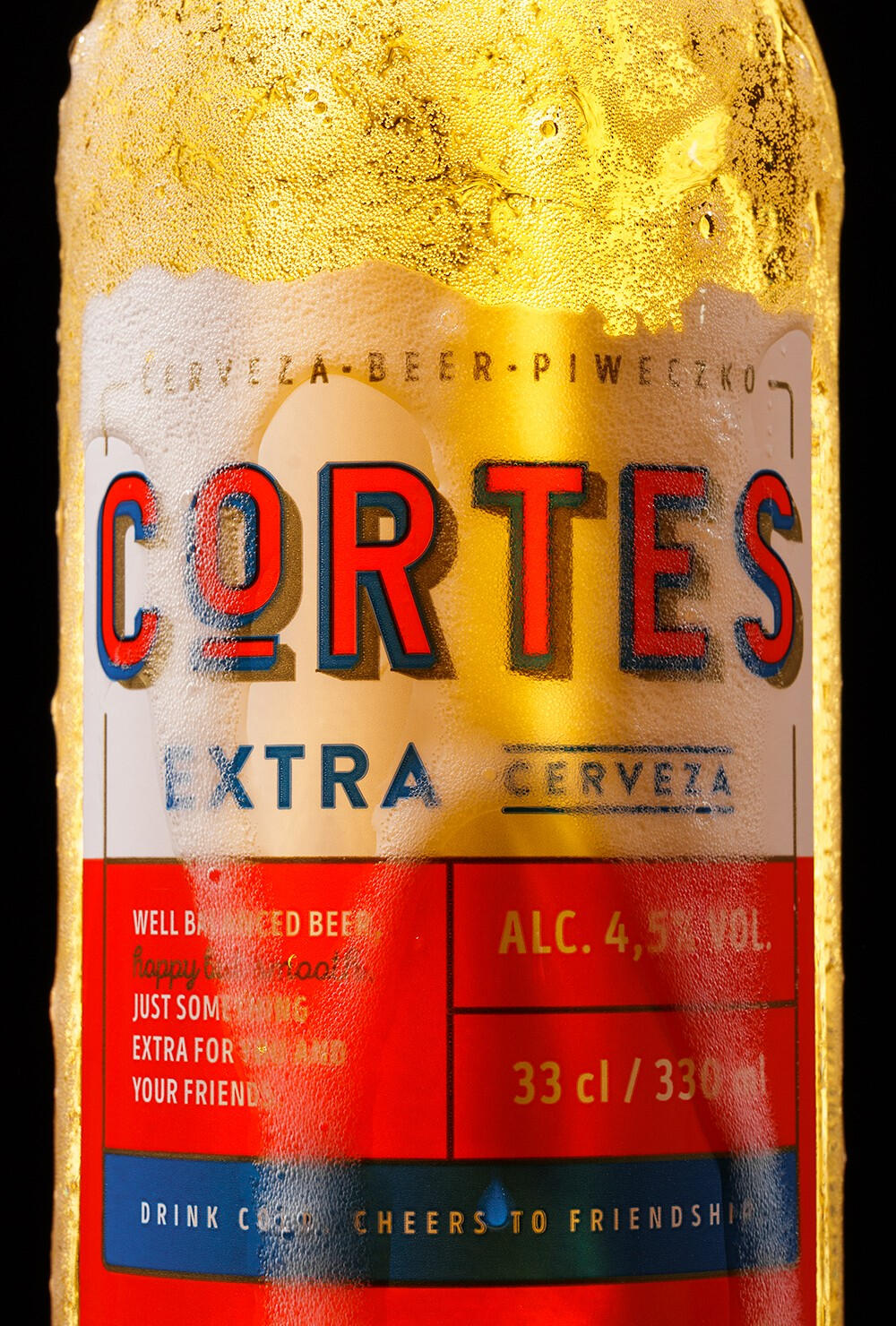 Macro shot of a label of Cortes beer with dramatic lighting and beer overflowing