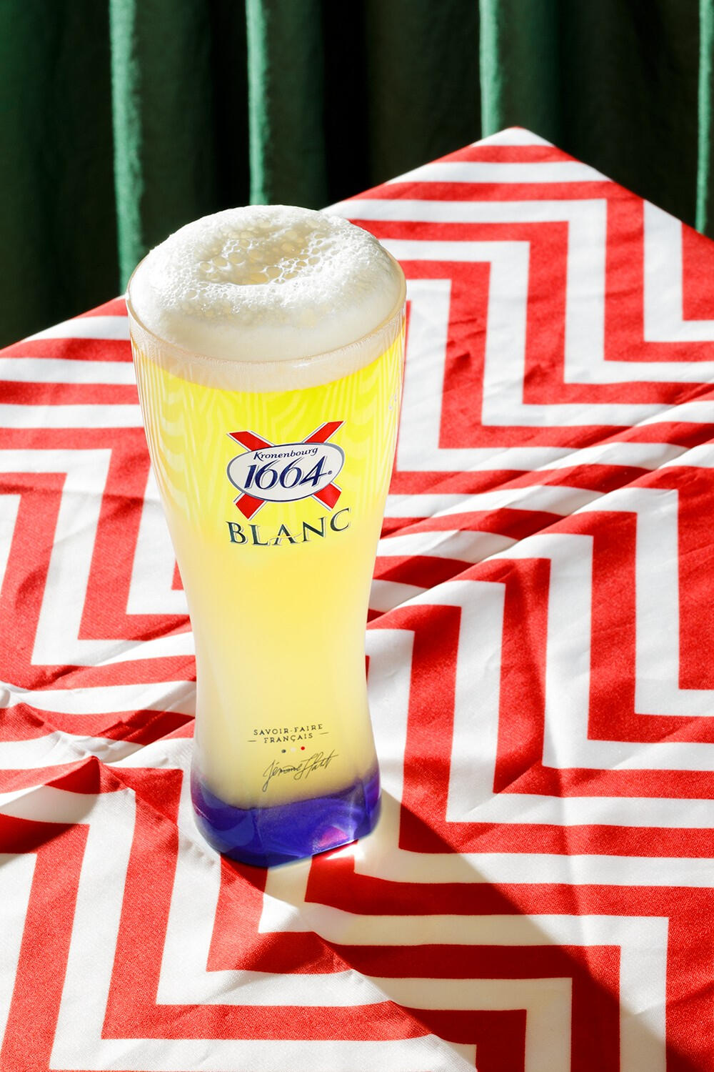 A glass of Kronenbourg beer on a trippy red/white table