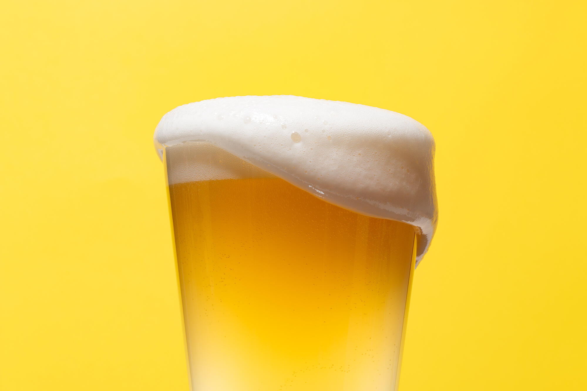 Playful image od beer glass full of beer on a bright yellow backgroun